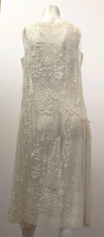 1920's floral lace wedding dress. Mesh side panels. Satin drop-waisted sash*. Pink satin ribbon rose detail on side. 

*not shown in photo silver-toned rhinestone faux belt buckle fastens sash