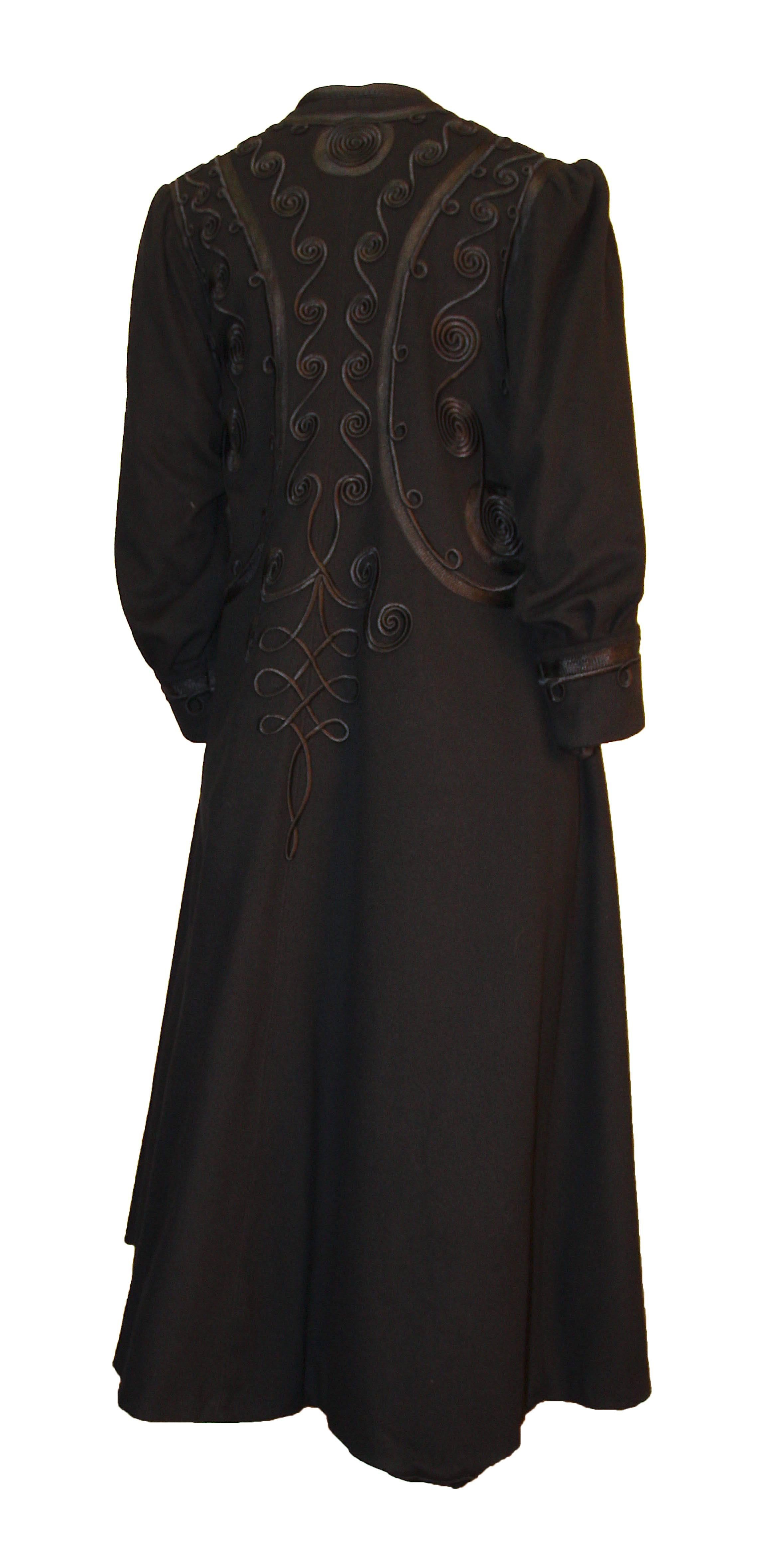 Edwardian black coat with elaborate silk trim throughout body and on cuffs. Slightly gathered at the shoulder. Buttons up the front. Fully lined in black silk.  