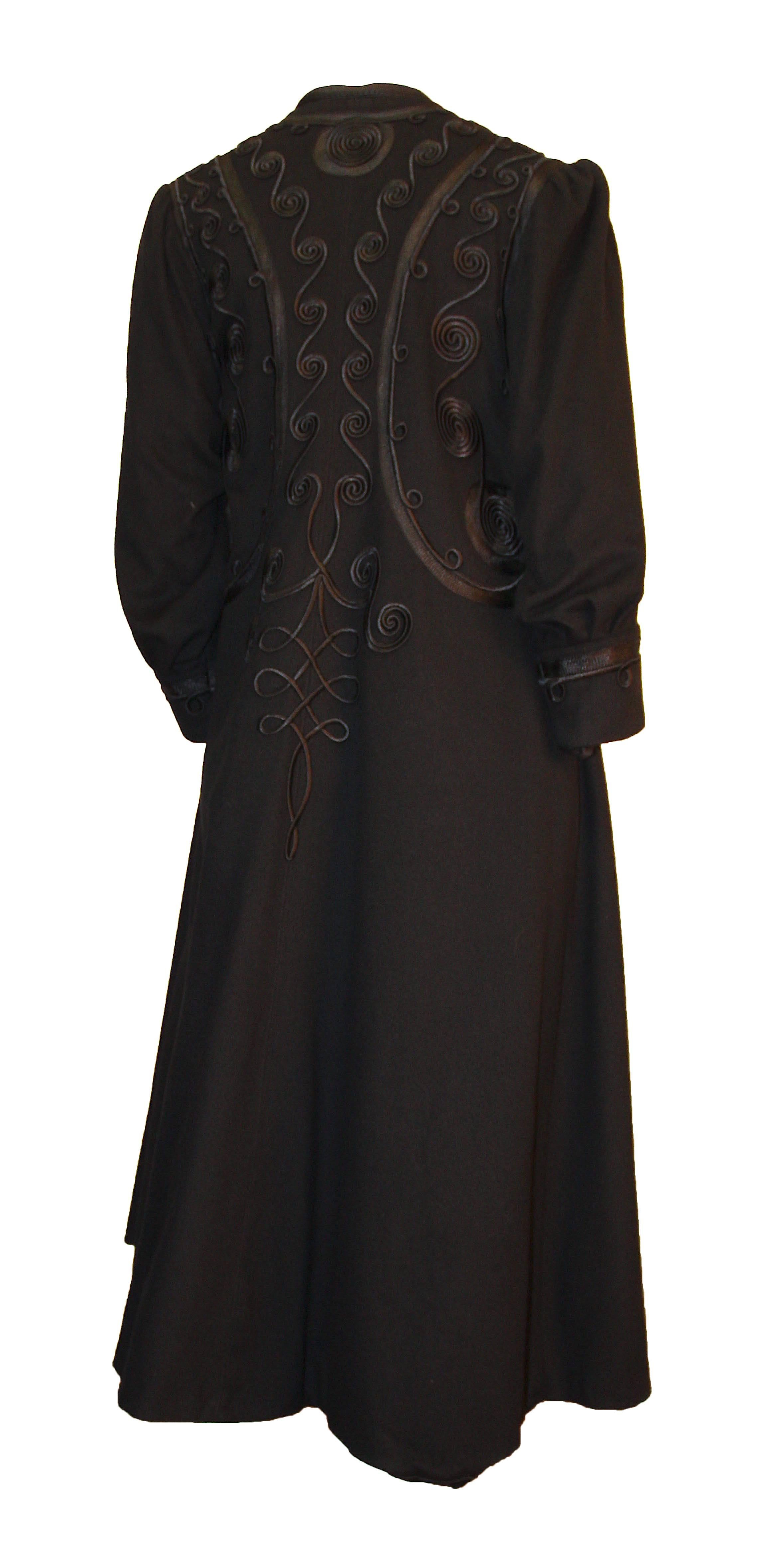 Cappotto nero edoardiano con elaborate rifiniture in seta su tutto il corpo e sui polsini. Leggermente arricciato sulla spalla. Bottoni sul davanti. Completamente foderato in seta nera.  