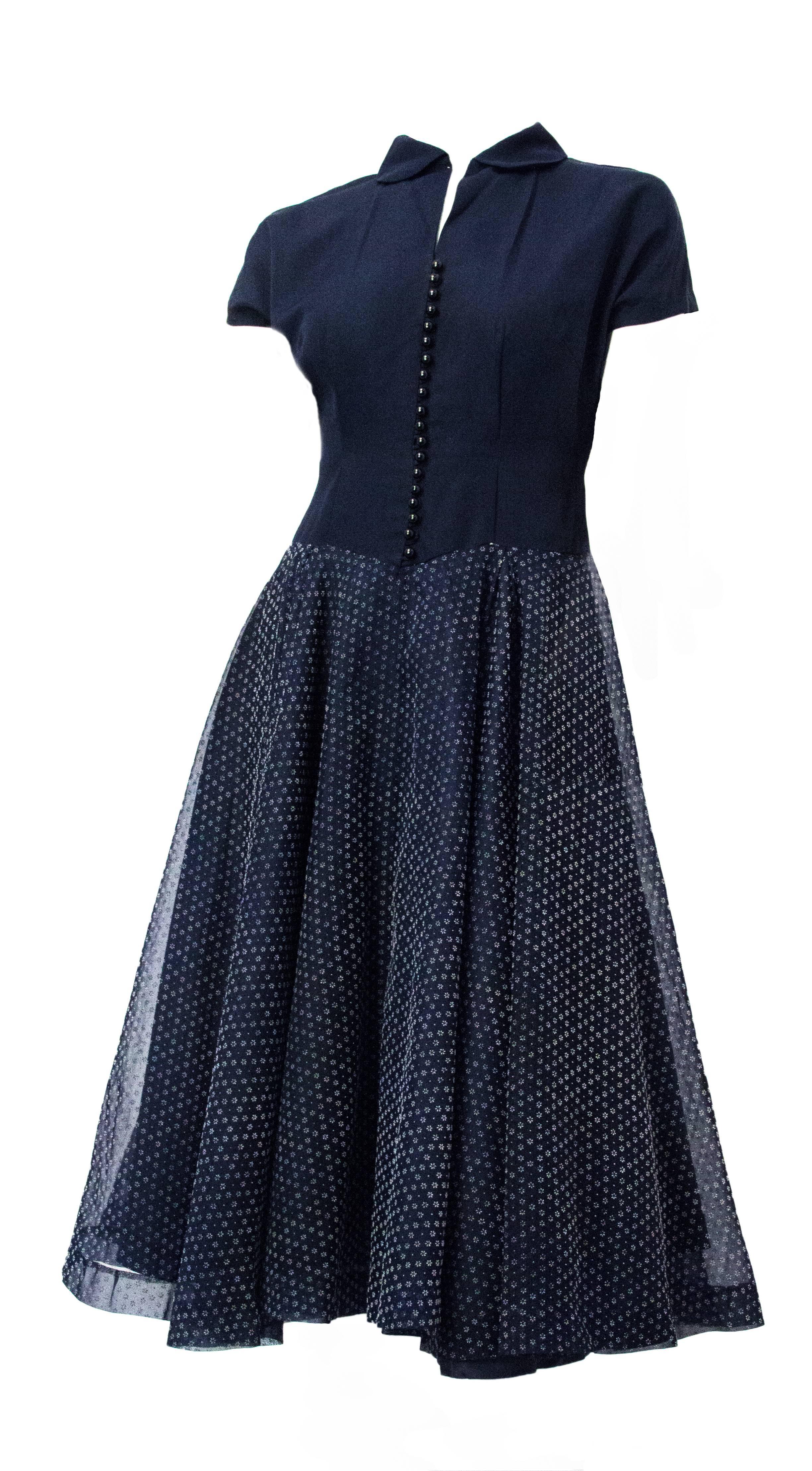 1950s navy day dress. Front button closure, as well as metal side zipper. Floral burnout organza skirt. Two box pleats on both front and back of skirt. Acetate lining. 

