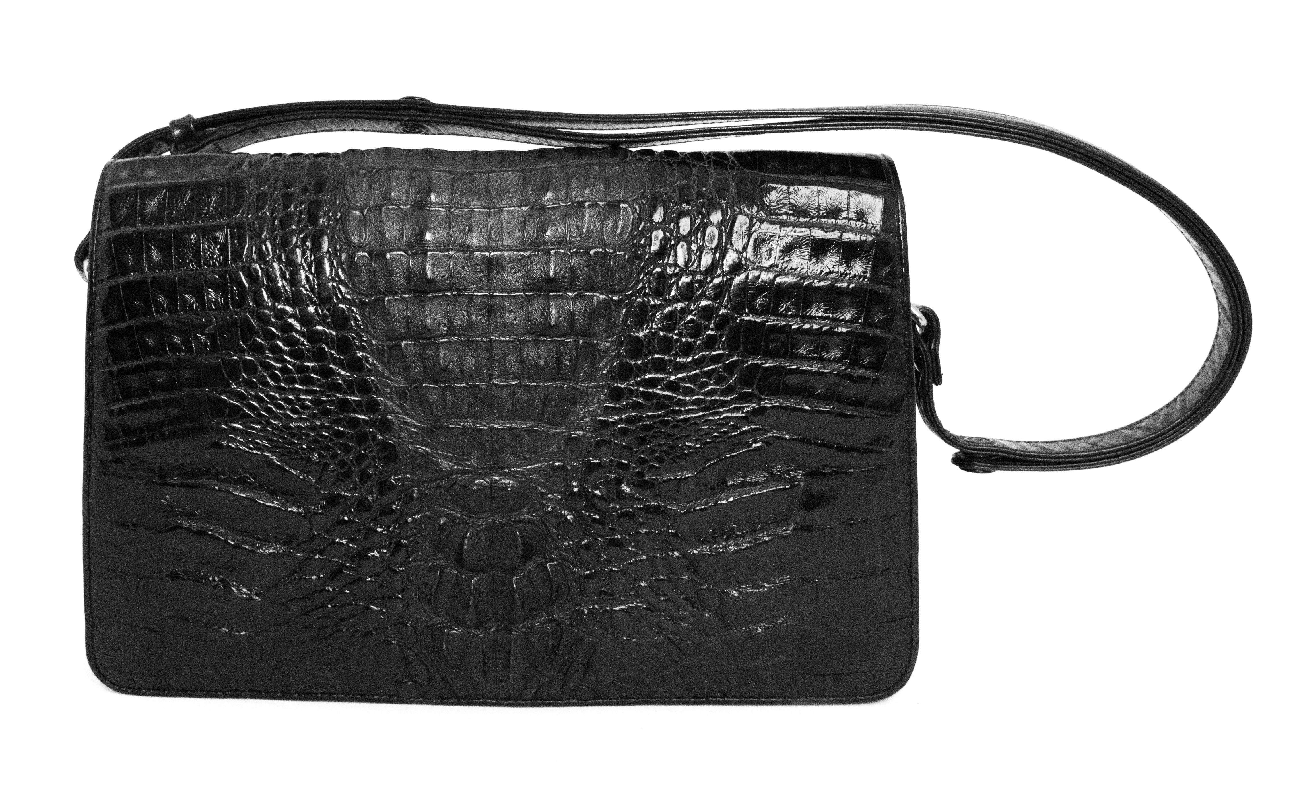 1980s hornback alligator purse in a true black. Gold toned hardware. Front opening flap with magnetic closure. Leather lining. Two main compartments, one zippered compartment, one side pocket. Snap closures on strap allows for conversion between top