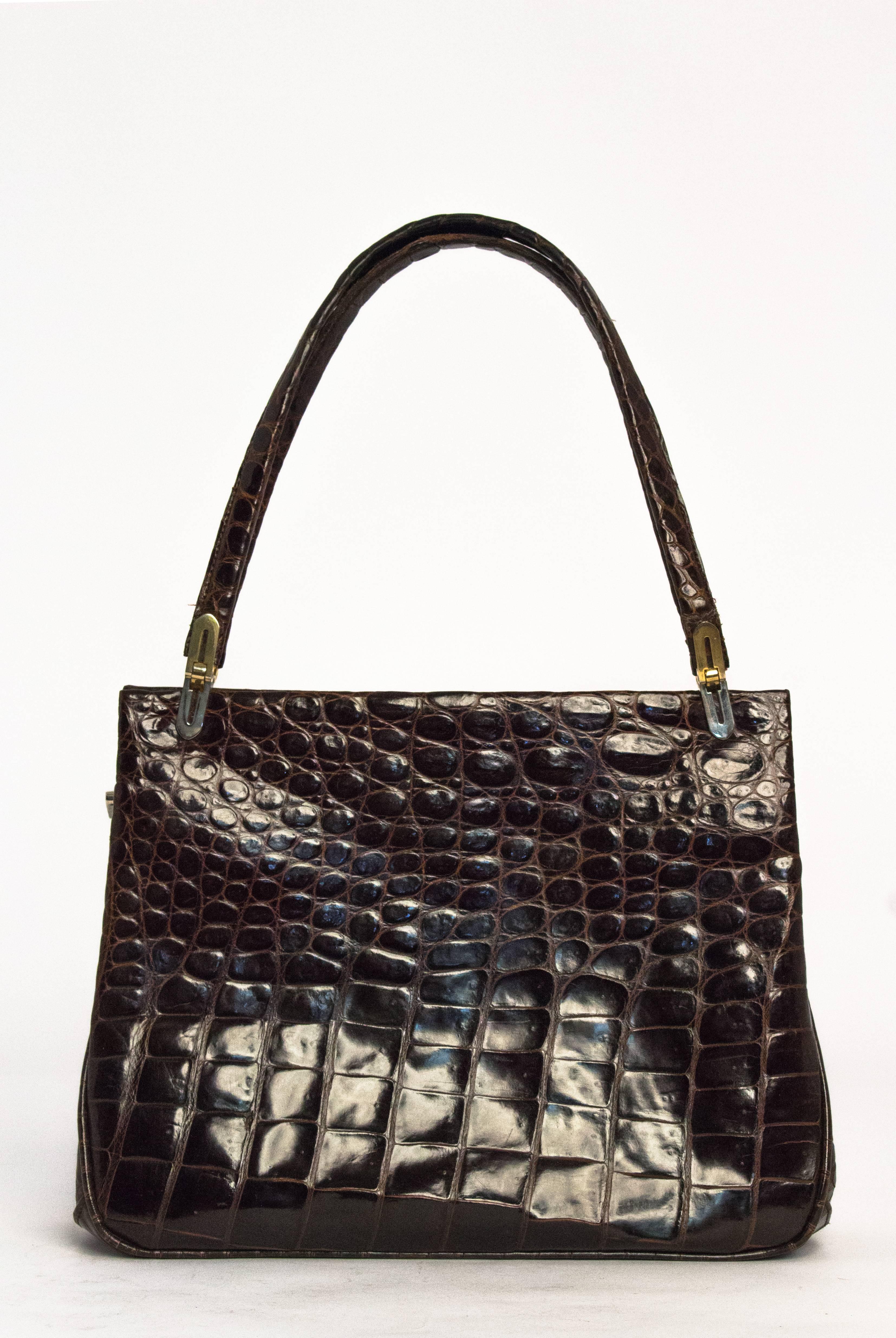 1960s chocolate brown alligator purse. Gold toned hardware. Leather lining. Two side pockets.

Strap length: 17"
Purse height: 8 1/4"
Purse length: 10 1/2" 
Purse width: 3" base