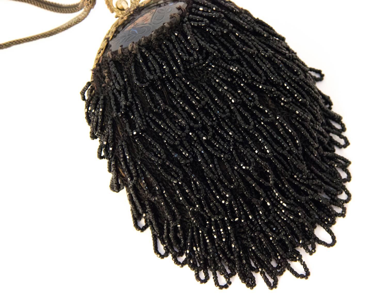 1890s victorian black beaded pouch with unusual hand carved frame embellishment. Filigree metal frame. Metal mesh strap. Lined in dark olive green cotton. 

Measurements:

Body of pouch: approx. 6 x 4 1/2 inches

Strap: 14 inches around ( 7