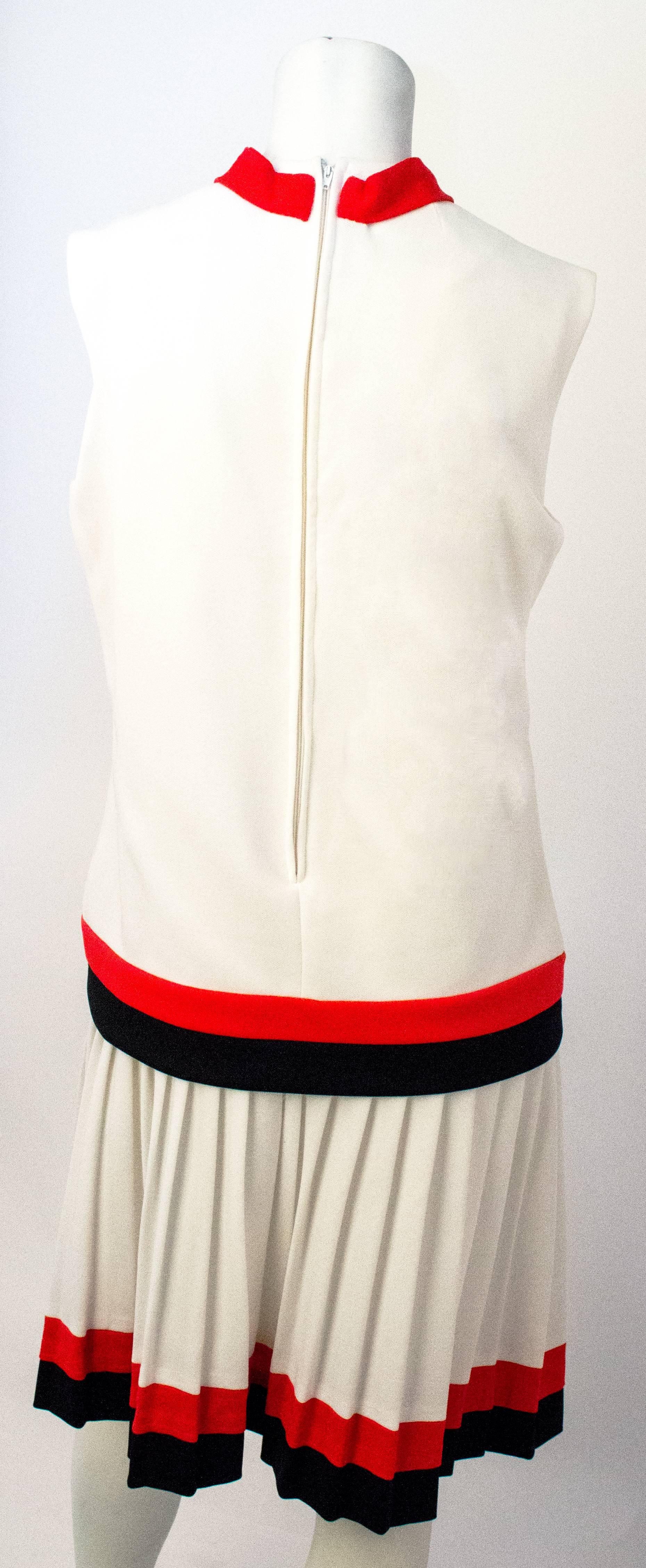 60s White Drop Waist Dress with Pleated Skirt and Red & Black Trim. Attached neck tie. Zips up the back. 