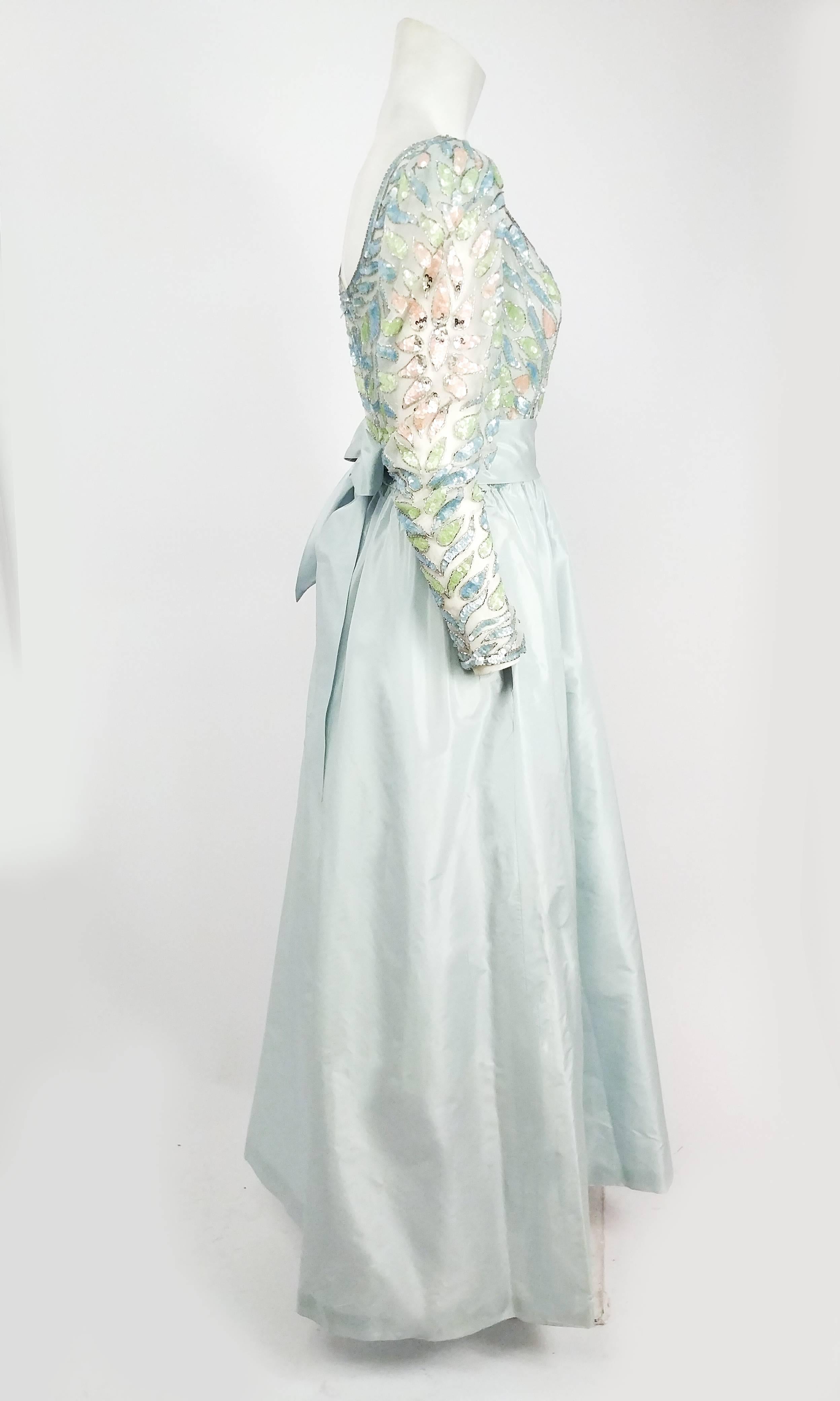 1960s Lillie Ruban Pastel Blue Beaded Silk Gown. Pink, green, and blue sequins and silver glass beads embellish the silk organza bodice, which has slightly puffed sleeves and low scooping neckline. Light blue taffeta skirt and separate waist sash.