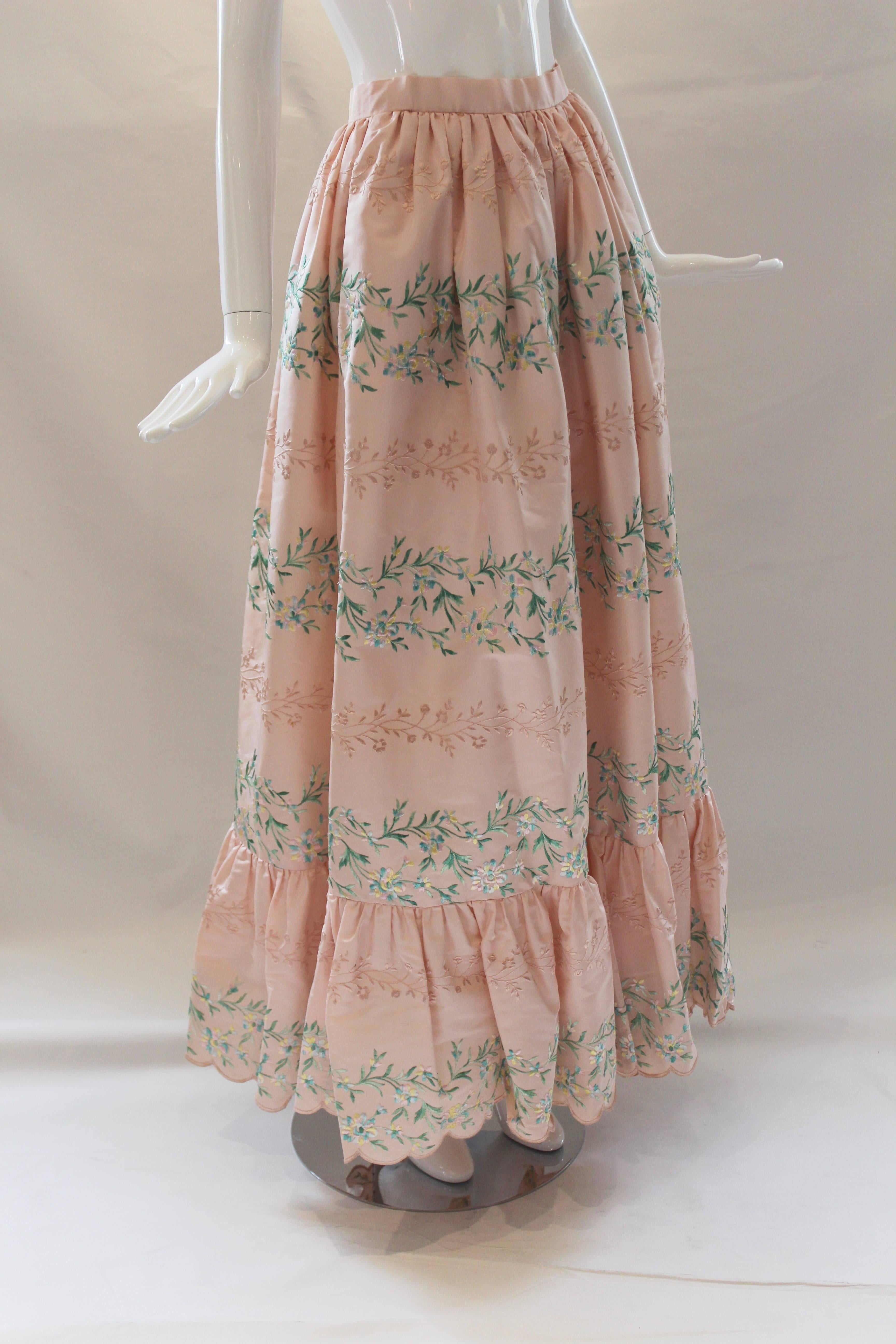 This luxe Oscar ball skirt is a gorgeous pale pink silk taffeta with embroidery throughout. Shades of mint green and pink flow though the embroidered vines and flowers.  Gathered waistline, ruffle flounce and scalloped hem add to the skirts feminine