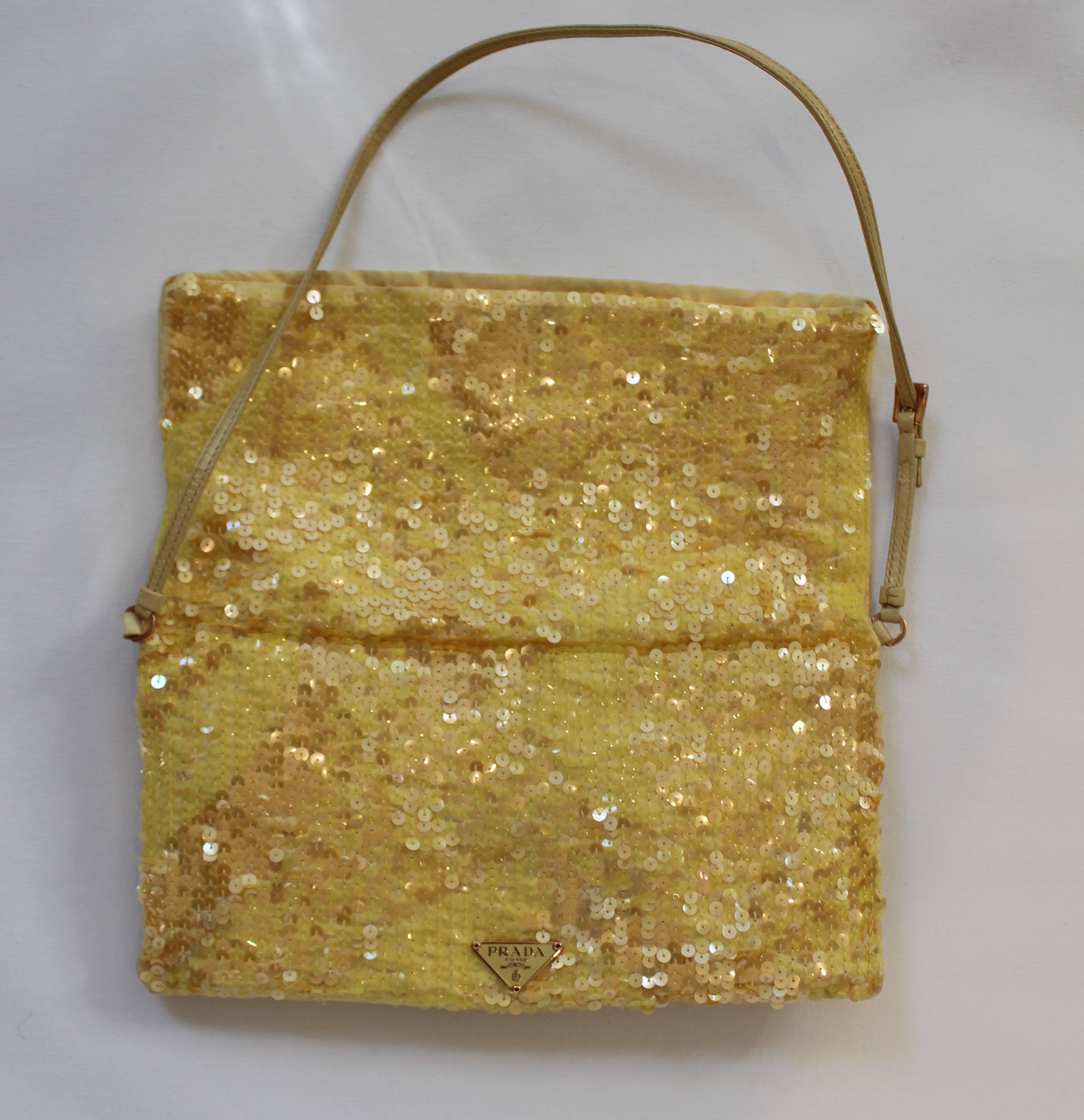 This darling Prada rectangular fold over handbag with satin lining makes quite the fashion statement.  The sunny yellow sequins are both clear and iridescent in nature.  The shoulder strap is made of yellow leather.  Bag features one interior zipped