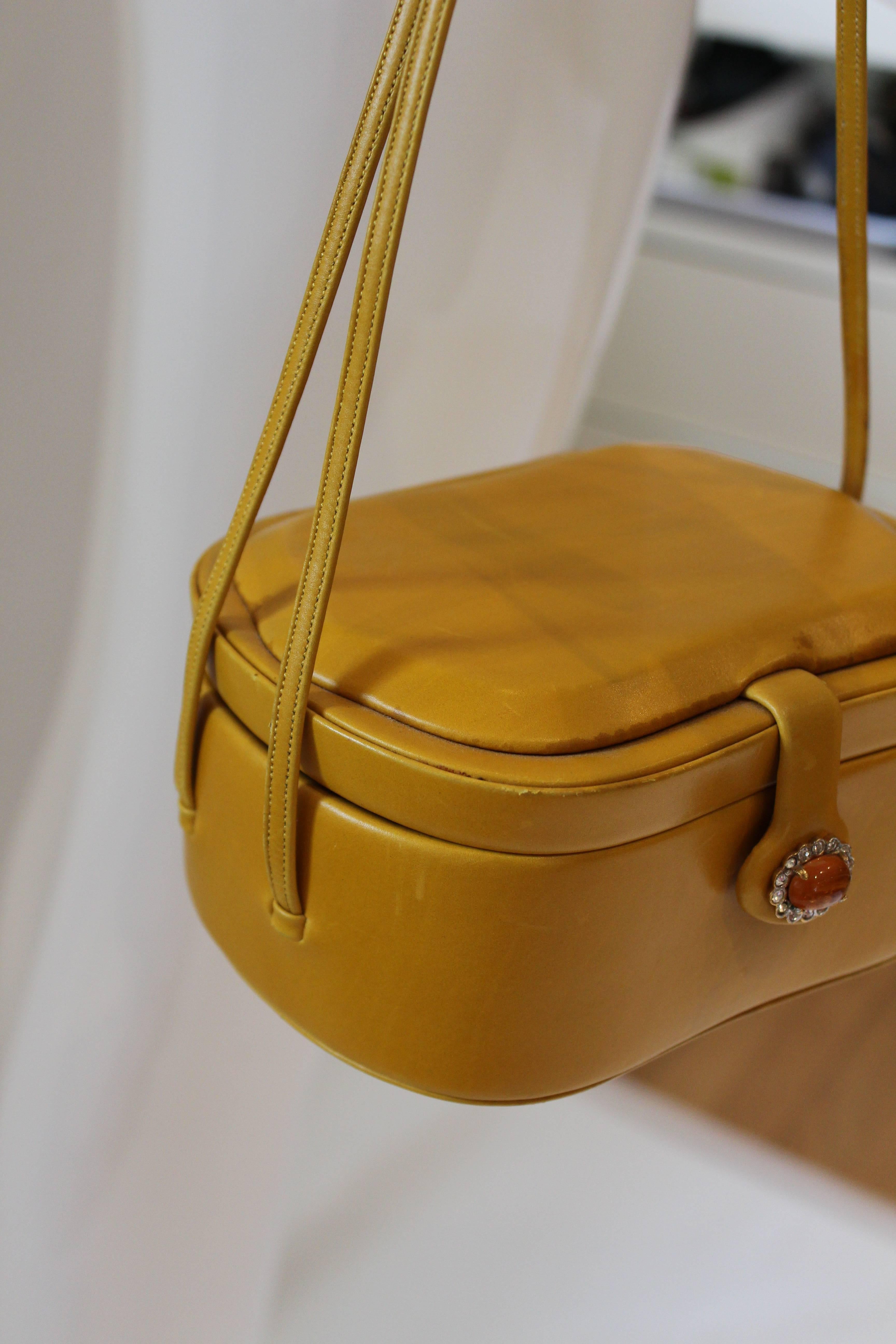 Measurements in inches: 
Strap length to bottom of bag: 11
Width: 6.5
Hight: 3
Depth: 5
This Judith Leiber box bag is fine mustard colored leather is quite a masterpiece. Features double strap, snap closure with yellow gemstone and rhinestone