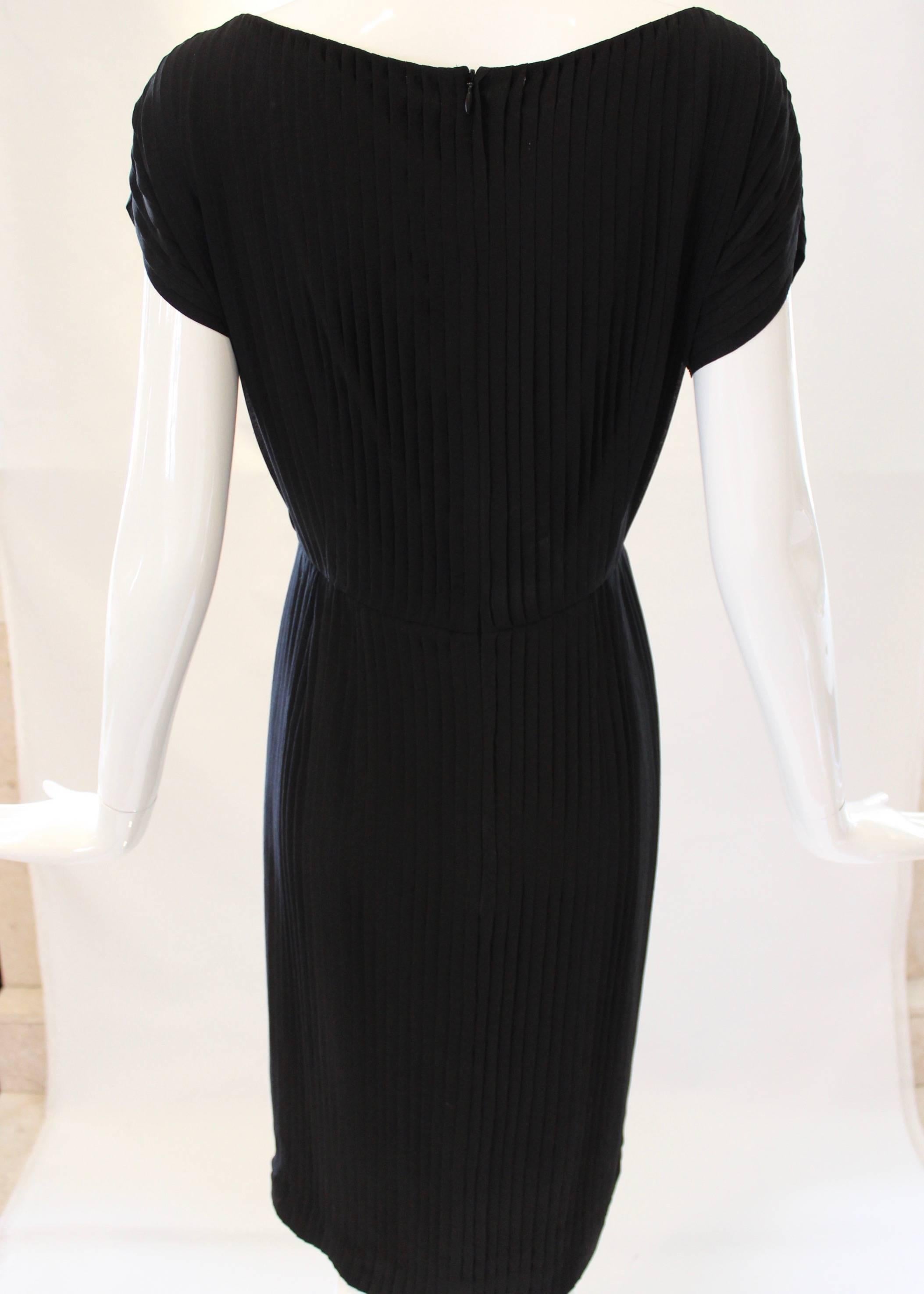 No wardrobe is complete without a stunning LBD! This black Akris dress boasts small pleats throughout, has a bateau neckline and features a hidden zipper at the back.. This minimalist style dress is cinched with an elastic waist and falls right at