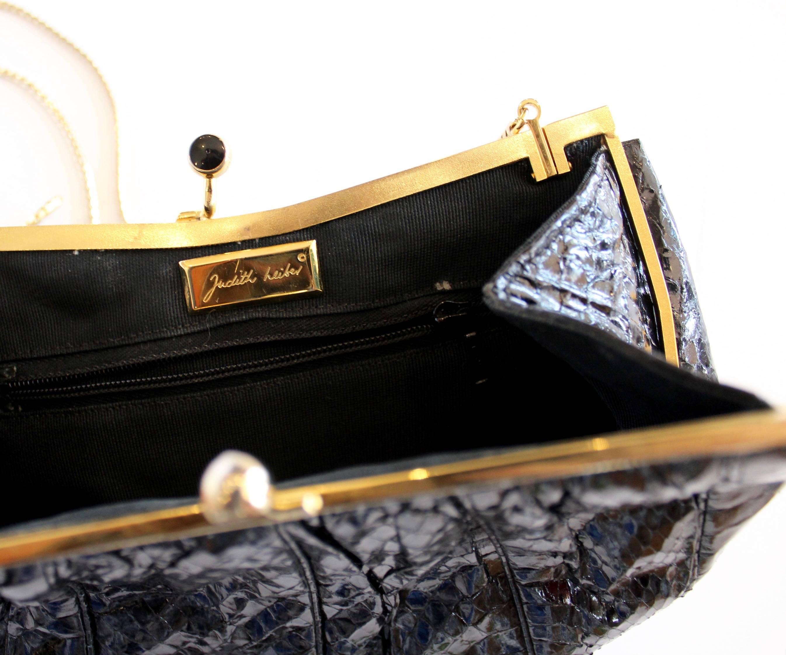 This black python Judith Leiber clutch has gold-tone hardware with black and red accents at its closure. Includes an optional gold-tone chain shoulder strap, perfect for a night out dancing!  The interior boasts a satin lining with a zippered wall