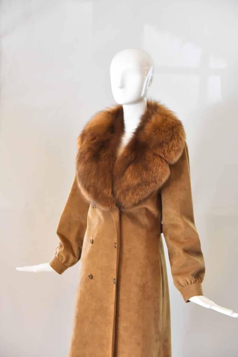 This beautiful Esther Wolf coat is made of a soft and luxurious ultra suede and comes in a creamy shade of beige. A wrapped belt cinches the waist and the inside is lined with a brown silk. Trimmed with a fox fur collar and finished with tortoise