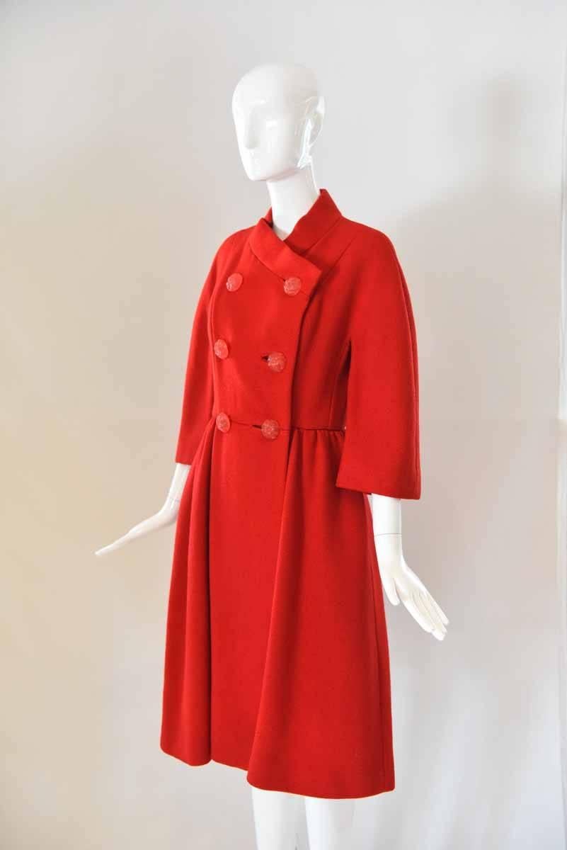 Strut into fall in style in this 1960s Neiman Marcus Red Dress Coat. The feminine silhouette is cinched at the waist and is finished with large red acrylic buttons and side pockets. 
Length: 42.5