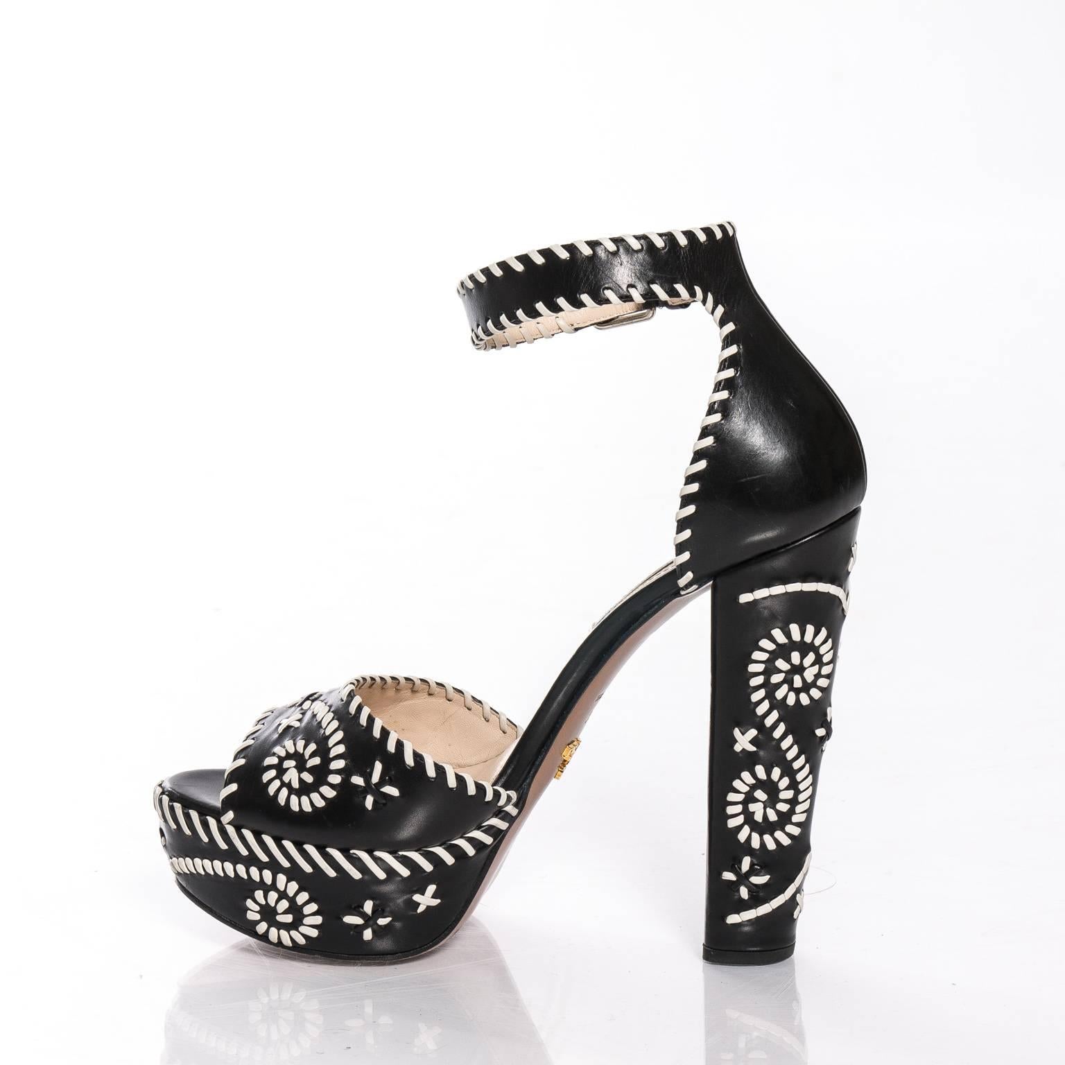 Pair of black and white whipstitch leather platform sandals by Prada. Peep toe and adjustable ankle strap. Made in Italy. Size 39.5. Lightly used.
