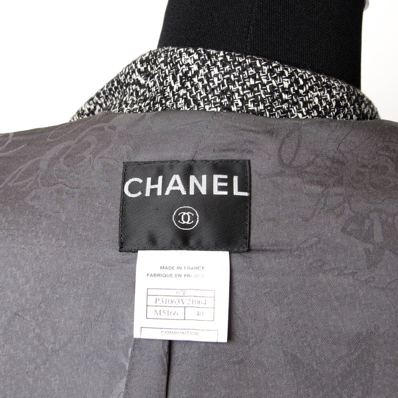 Chanel Black and white tweed blazer. Features two smaller pockets near the chest and two larger pockets below. Large silver tone buttons featuring the 