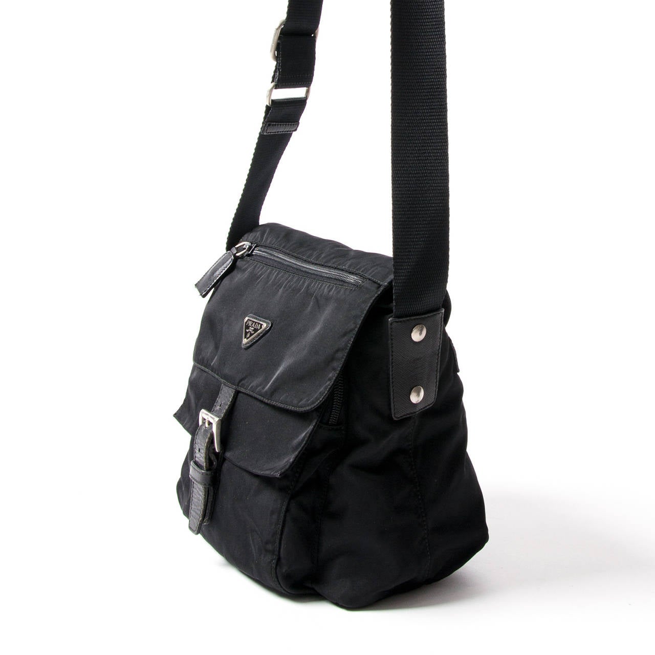 Prada Tessuto messenger bag in black nylon fabric. This handy bag features 3 seperate zipper compartiments and one central compartiment. The bag closes with a silver hardware buckle on the front.
Long strap to be worn across body.