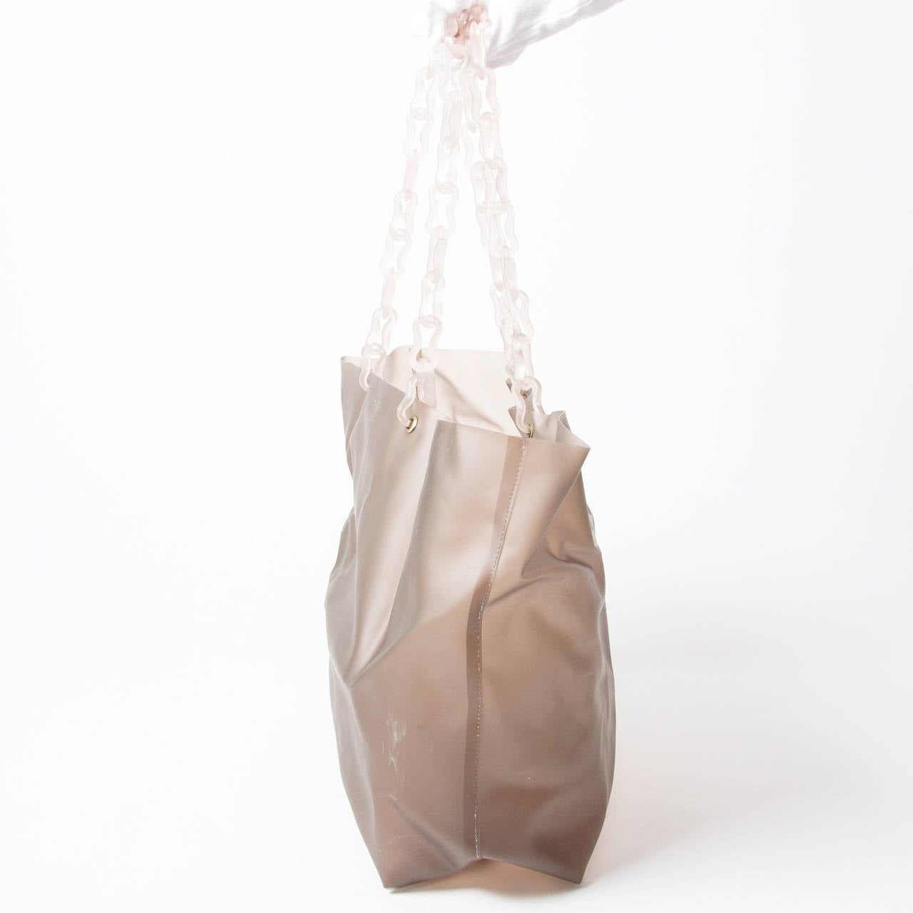 A taupe-colored tote bag by Prada, made from hard plastic. The plastic chain handles allow you to wear it as a shoulder bag. The perfect bag to add a touch of chic to your casual outfits. Prada Nude Transparant Plastic Tote Bag