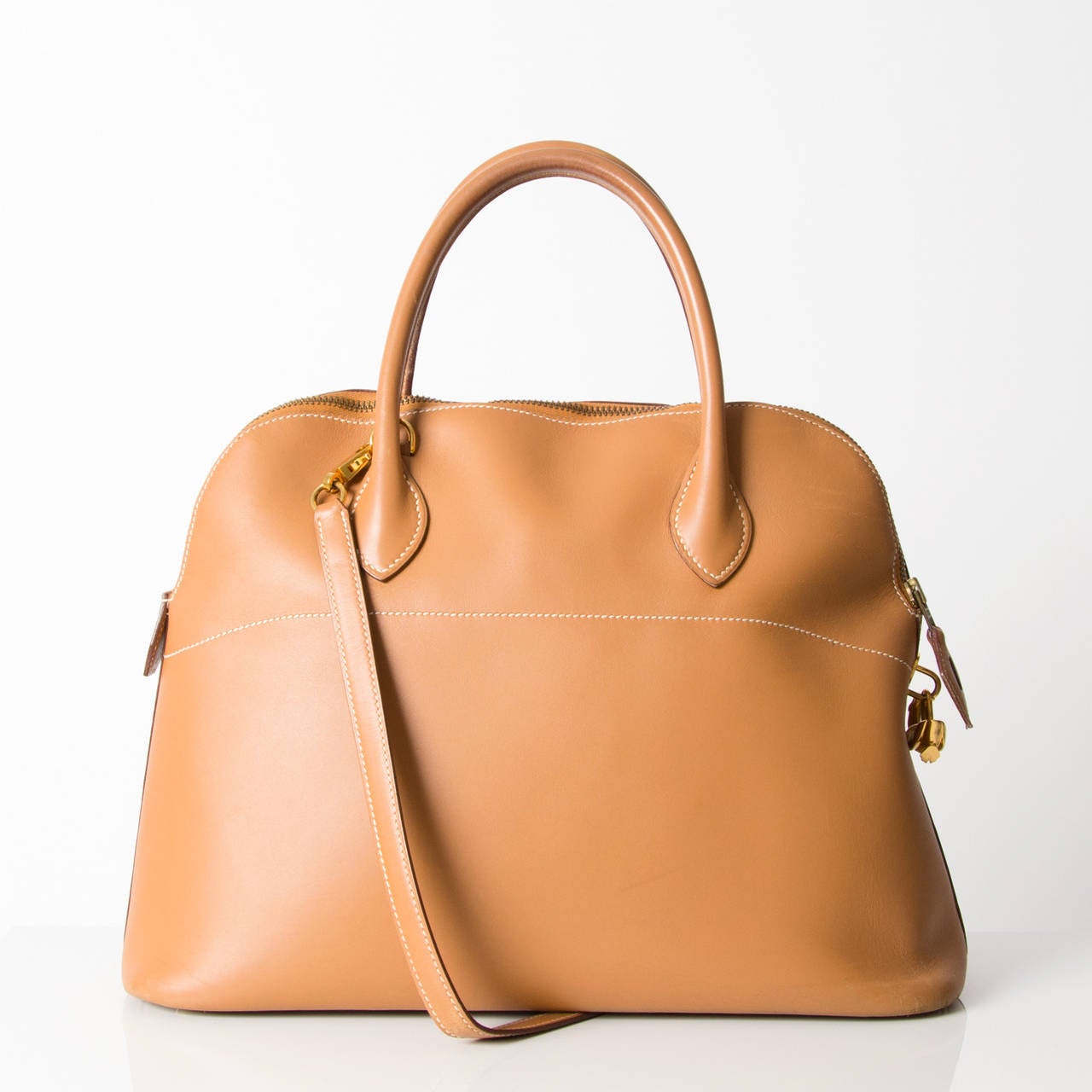 The Hermès Bolide Gold is a classic bag, which unquestionably embodies femininity and class. It is a domed top handle bag with a zip around closure. The gold hardware adds a luxurious feel to this stunning piece. The interior features very smooth