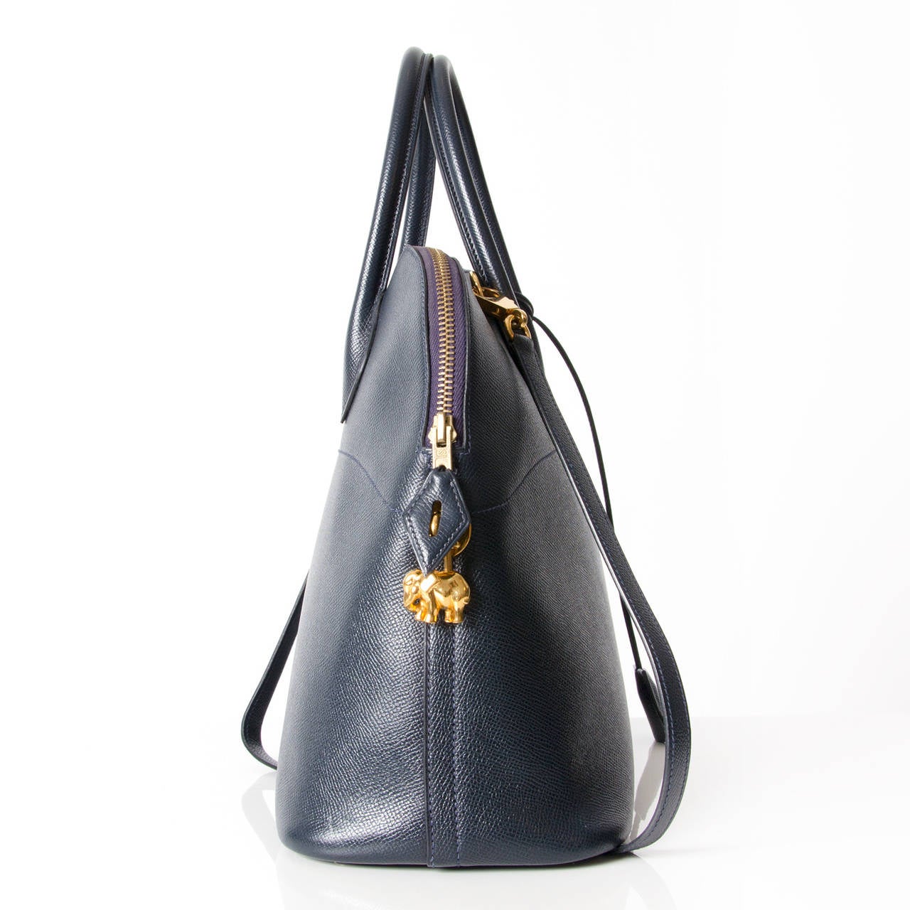 The Hermès Bolide in navy blue leather is a classic bag, which unquestionably embodies femininity and class. It is a domed top handle bag with a zip around closure. The gold hardware adds a luxurious feel to this stunning piece. The interior