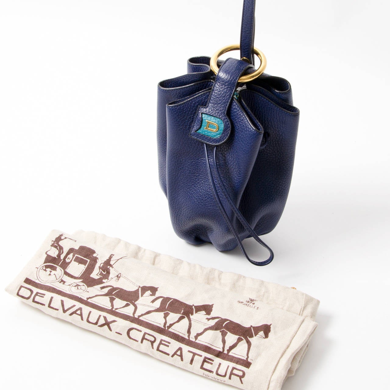 This authentic vintage bag by premium Belgian leather goods brand Delvaux features a lovely peacock blue hue and gold hardware. A long adjustable strap enables crossbody and over the shoulder wear. A magnetic front closure and all-around strap to