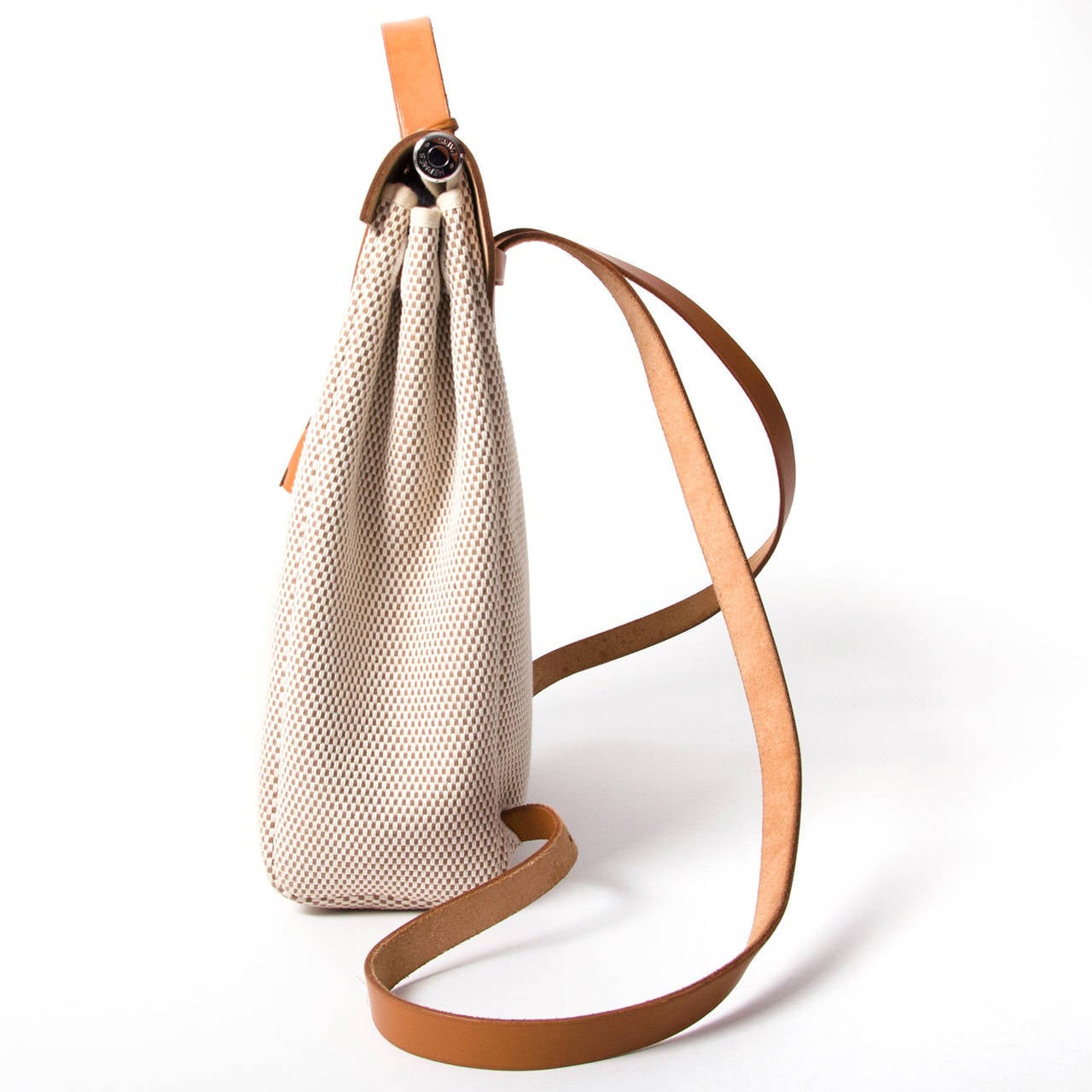 Similar in look to the iconic Kelly bag, this Hermès Herbag comes in woven white and beige canvas with cognac leather detailing. This model, the Herbag, was re-released in 2009 with an added zipper. This particular one however is the original