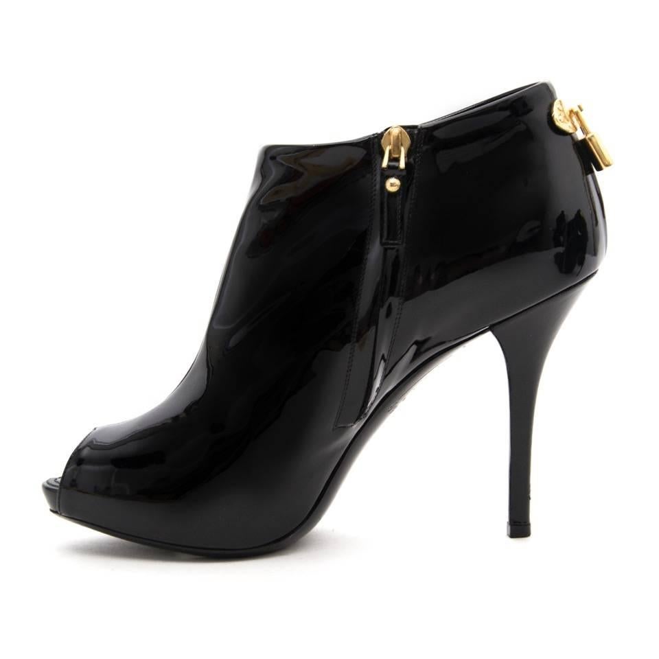 Louis Vuitton patent leather booties in black with gold hardware. Elegant high heeled booties with a peep toe. The back of the heel features the iconic LV-locket. Comes with dust bag. 