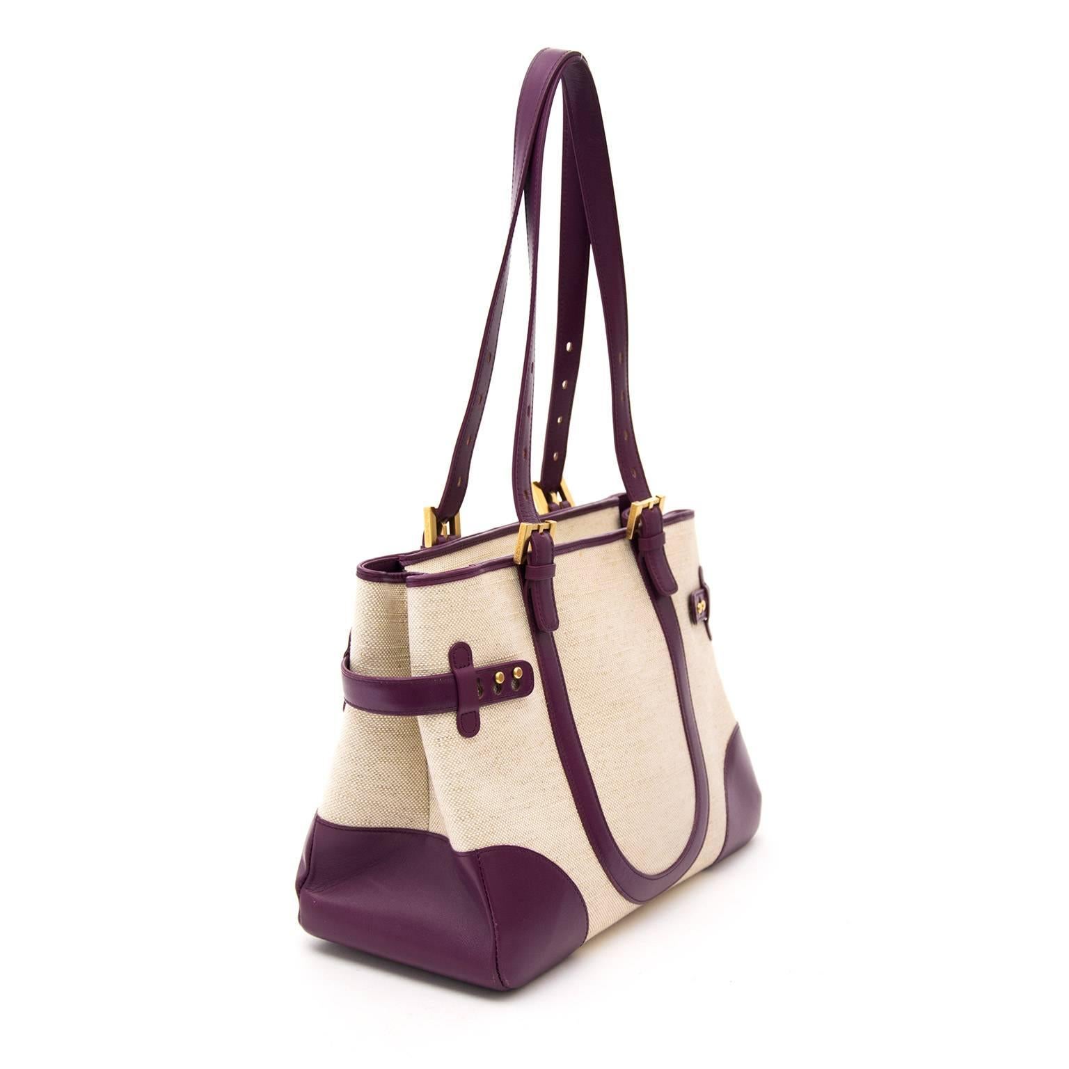 This unique Delvaux Tempête City comes in a light colored canvas with purple leather details and gold-tone hardware.  Shoulderstraps are adjustable which makes the bag easy to wear.  Closes with a topzipper.  Small pocket in the front.  Interior