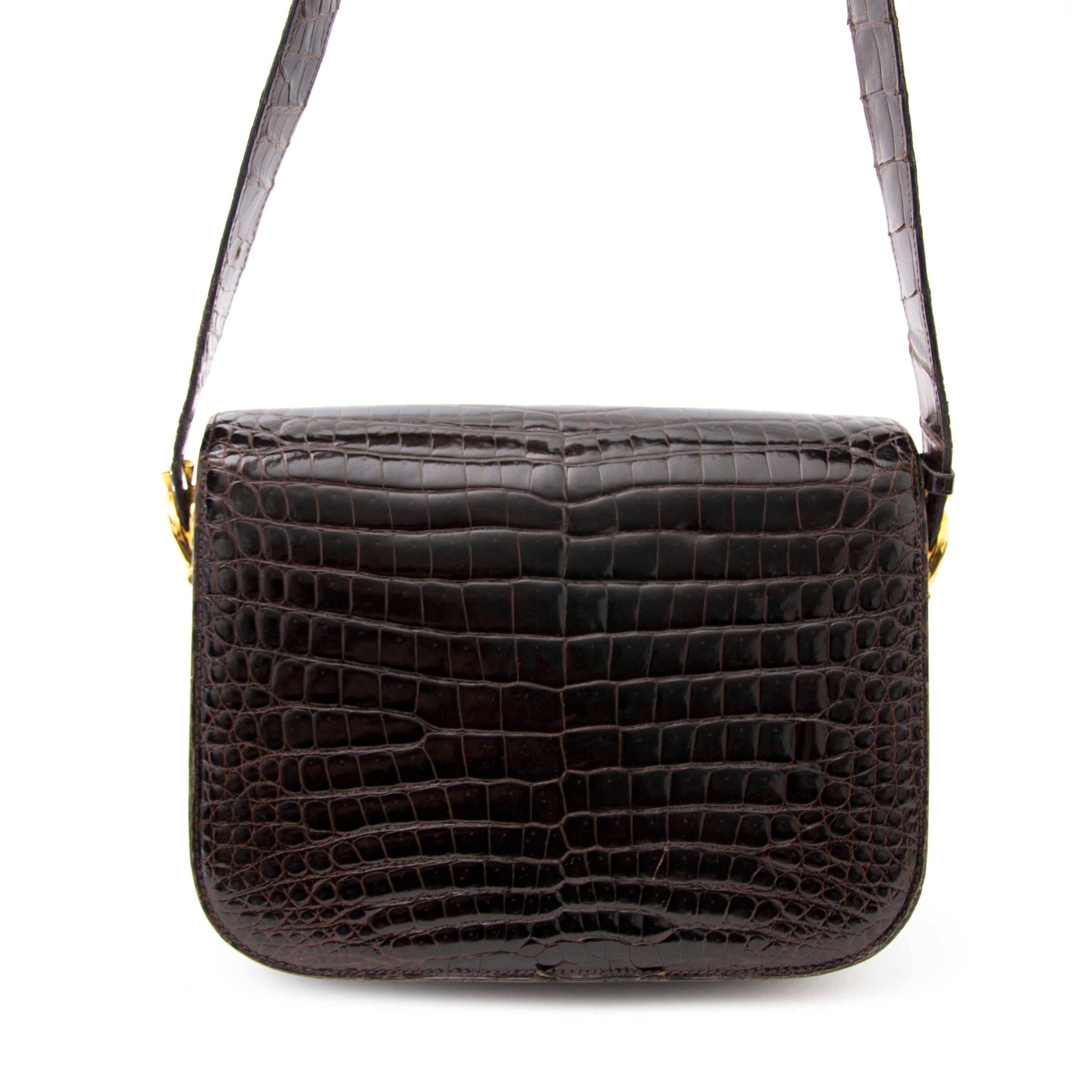 Up for offer today: this unique Céline vintage horse box bag crafted out of precious alligator skin.

Its rich brown color and gold toned clasp and hardware add to the luxuriousness of this bag.

The bag closes by sliding the front flap inside the
