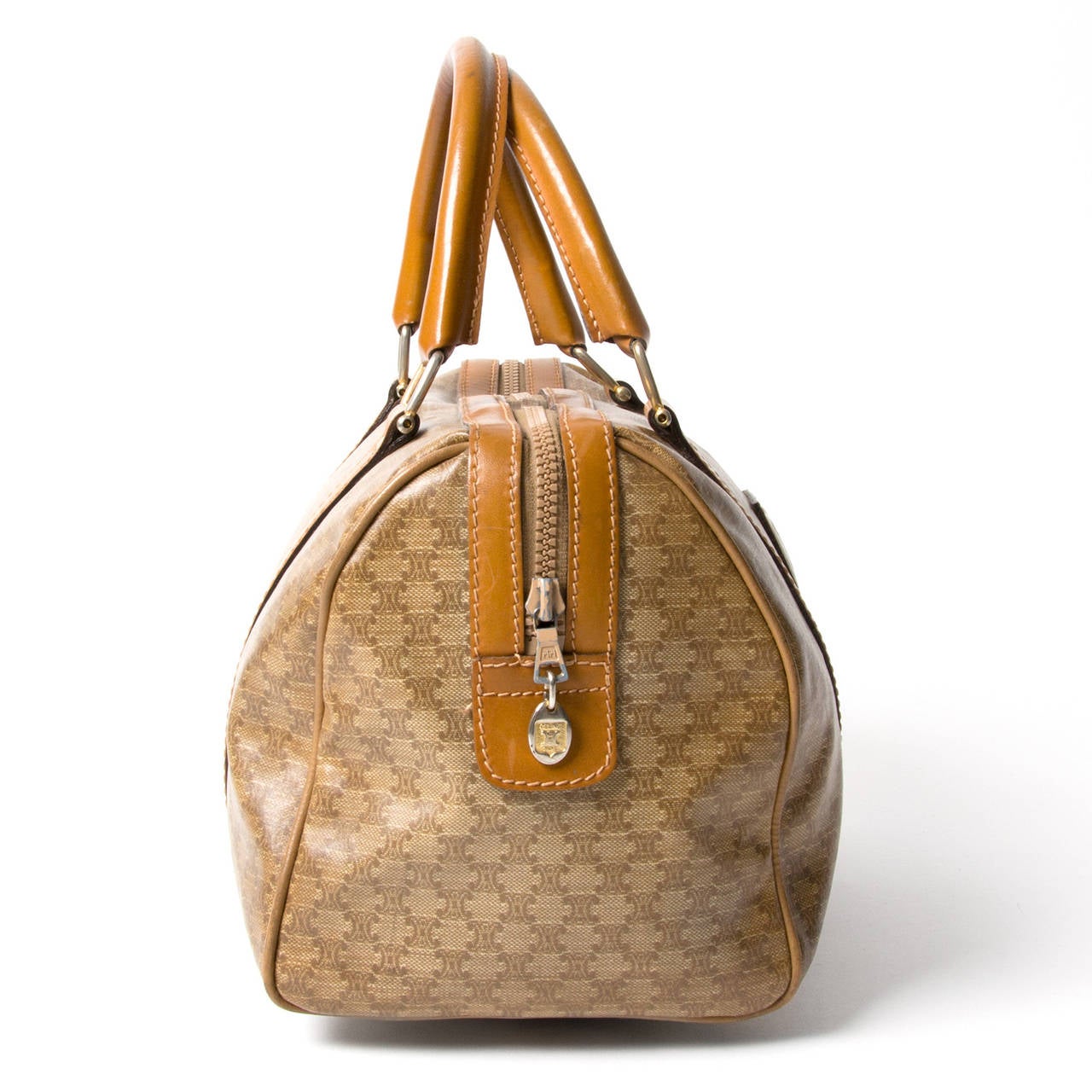 This Céline bag with monogram material and tan leather detailing and top handles comes in a classic round speedy shape. It's a practical size and thus very handy to carry around all your favorite items when you're dashing round town. The gold