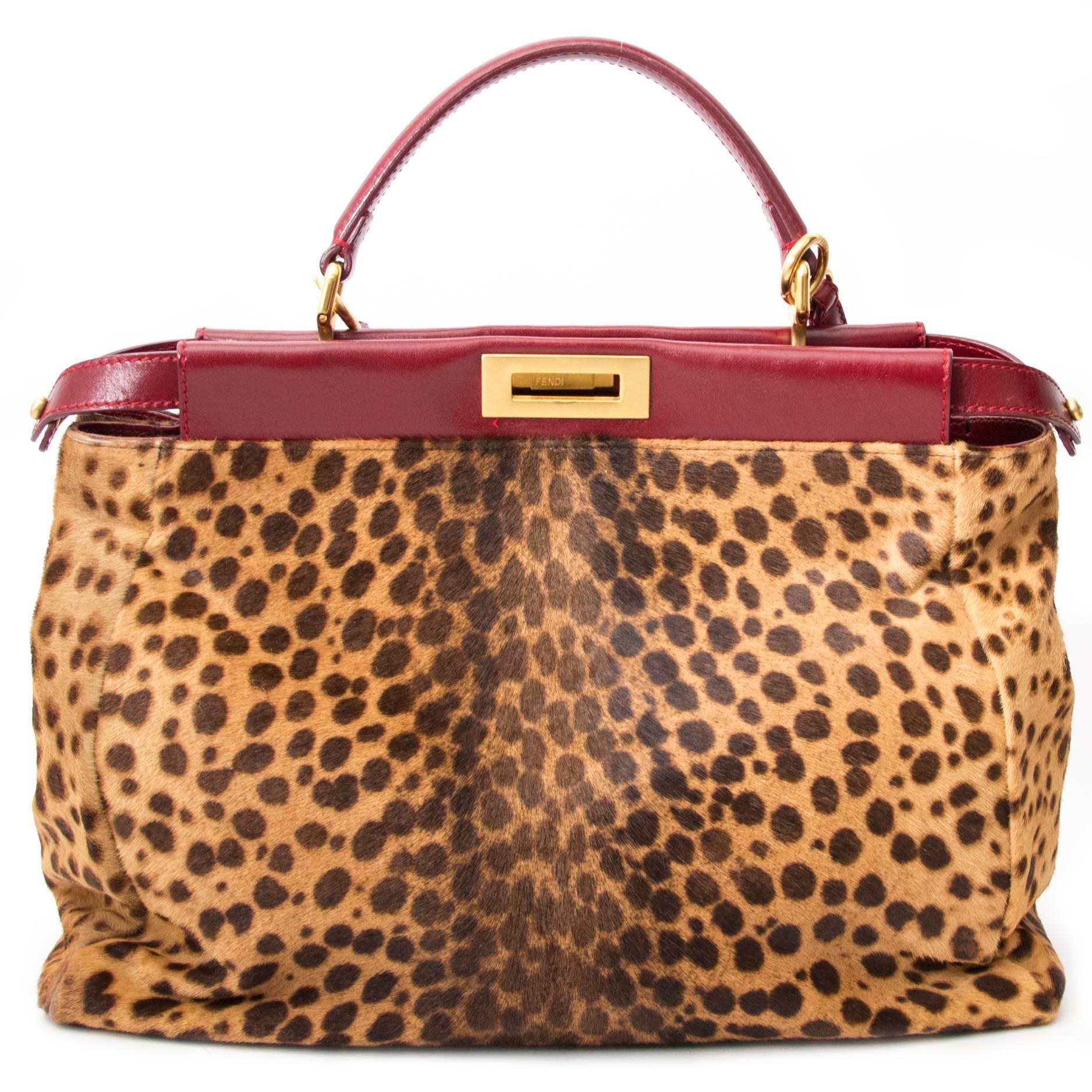 This lovely Fendi Peekaboo in a large size features burgundy leather and leopard print pony hair. The bag has a detachable shoulder strap. In very nice condition.  Branded gold toned turnlock hardware. Interior is two large compartments lined in the