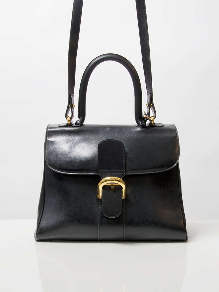 Delvaux black Brillant MM bag in box calf leather. Rolled leather top handle and distinctive buckle closure. Gold hardware. Strap included. 