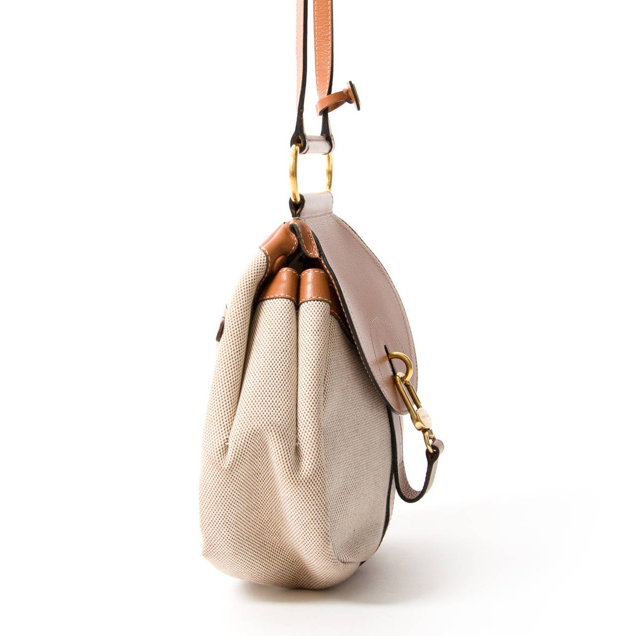 Delvaux Cerceau crossbody bag in sand colored toile and cognac leather. Gold hardware and gold top bar to hold the shoulder straps.

You can wear this classic bag as a shoulder bag or as a backpack, for more practical use.

Zipper compartment on