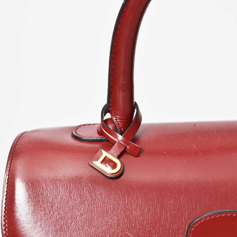 Delvaux Brillant MM handbag in burgundy red with gold hardware. Rolled leather top handle and distinctive buckle closure. 