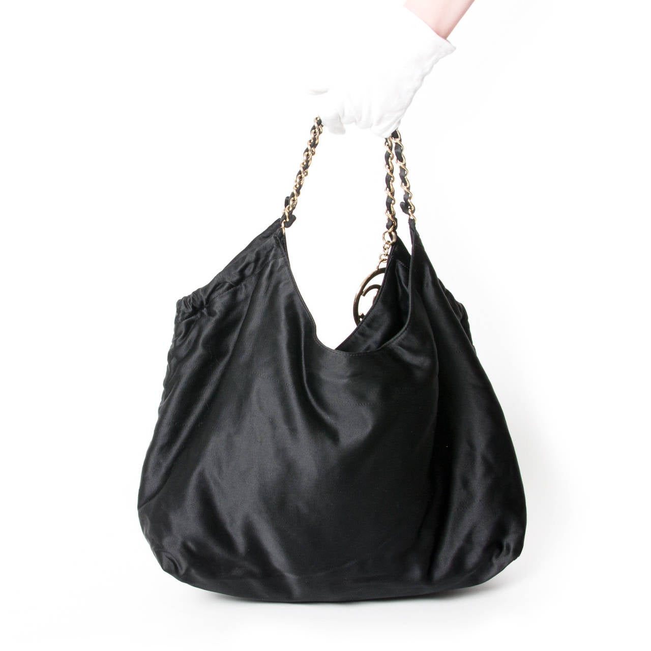 Black satin Chanel Coco Cabas

This tote with gold-tone hardware has a medallion with the Chanel logo.

The bag has a satin lining, interior pockets, detachable make-up bag, chain shoulder straps and magnetic closure.

On the frontside is the