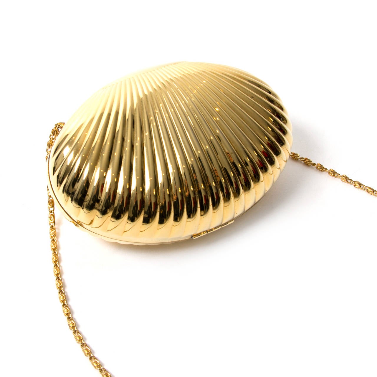 Dolce & Gabbana Goldene Muschel-Clutch. 

Kleine Clutch in Muschelform aus glänzendem Metall. 

DG-Logo auf der Vorderseite mit Kristallen verziert. Metallband zum Tragen über der Schulter. 

Futter mit Leopardenmuster