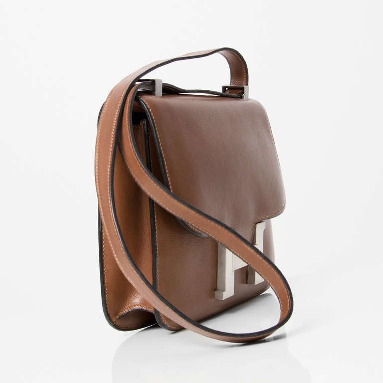 Hermès brown Constance shoulder bag with brushed palladium hardware. The interior features an open pocket and a zipped pocket.