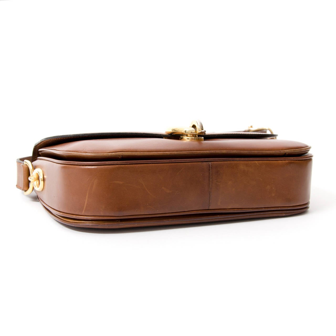Adjustable shoulderstrap and gold metal hardware. Buccle closing. Leather inside features three compartments.
Middle compartment contains two small side pockets and back compartment features zipper bag.
