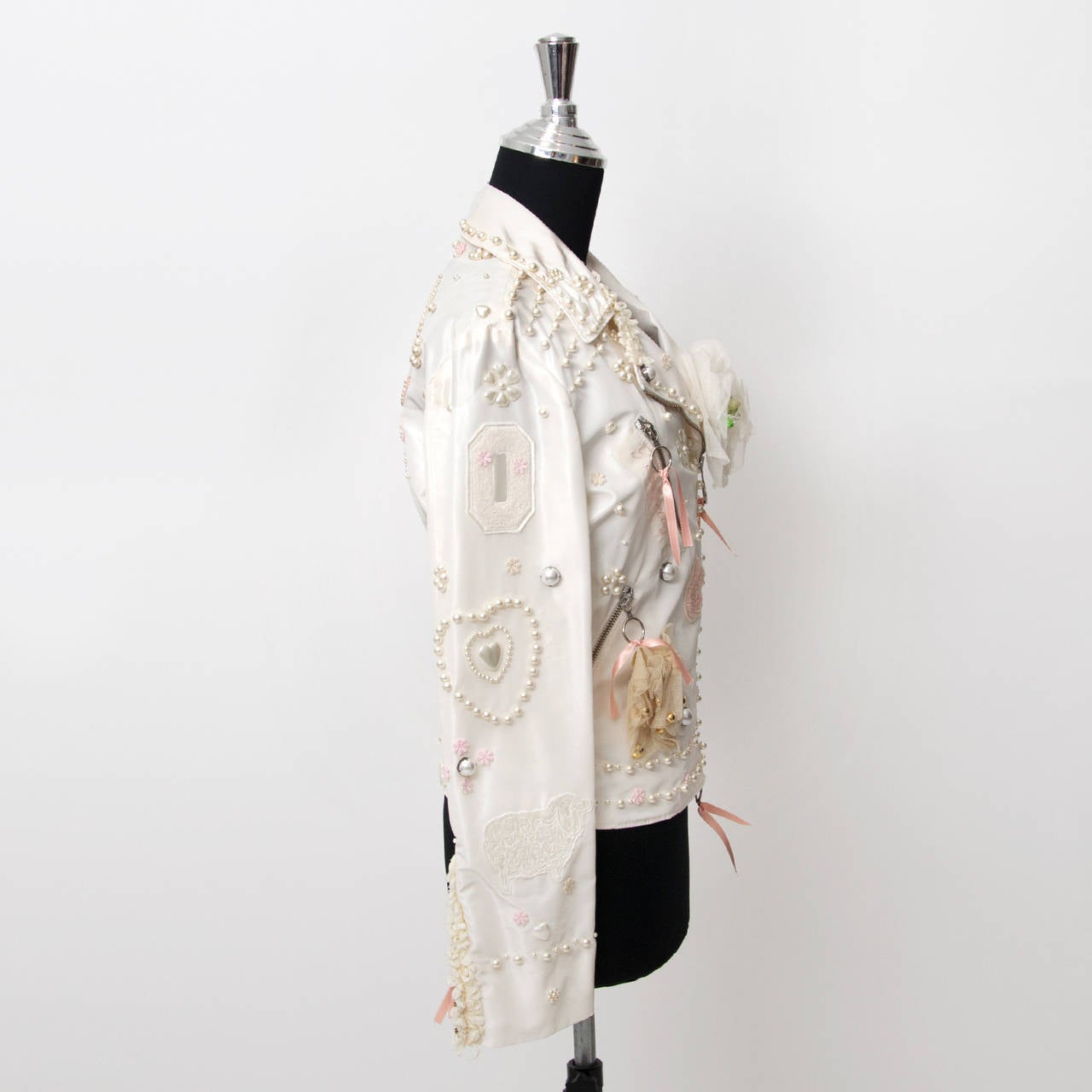 Stunning Moschino perfecto jacket in white cream colored silk blend fabric. Embellished with pearls, bows and flower details. Pink wings appliqué on the back. A musthave for true fashionistas.