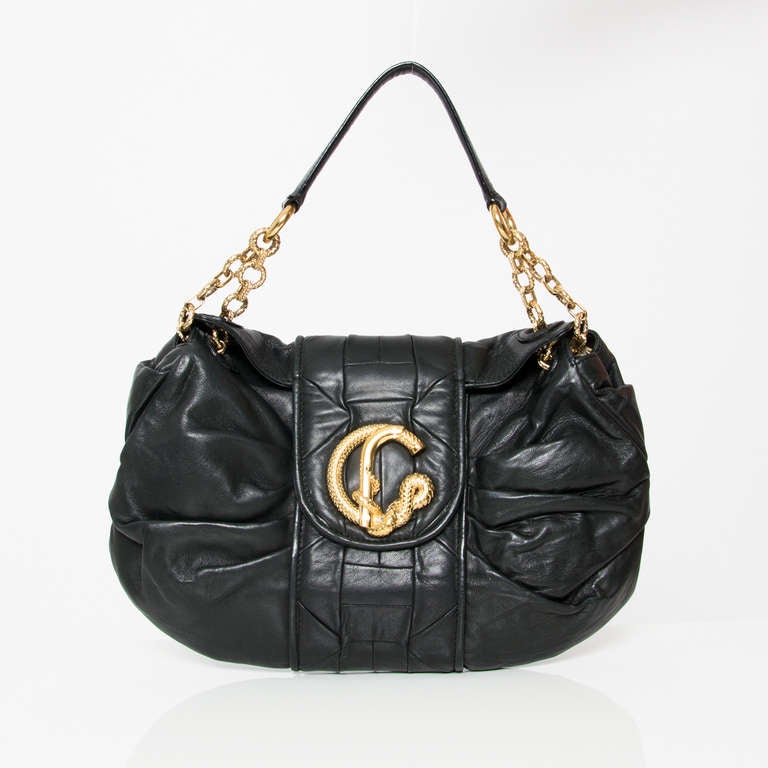 Black leather shoulder bag by Roberto Cavalli. This bag has a fold over closure with golden hardware in the form of a snake. It can also be used as a clutch.

Measurements: 
Width 13