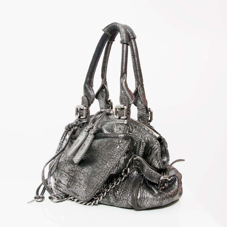 Flashy yet classy Chloé handbag made from shiny silver metallic leather, with roomy interior. This trendy Chloe Paddington Capsule shoulder bag is in Pre-Loved condition. It is made from metallic leather and accented with gold and silver-tone