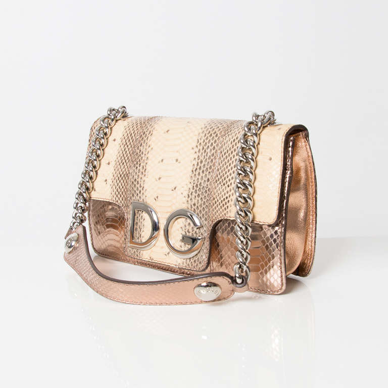 Dolce & Gabbana rose metallic snake print shoulder bag. Silver chain and leather strap. Silver toned hardware.

Magnetic push button closure. Open pocket beneath the flap.

The interior features a zipped pocket.