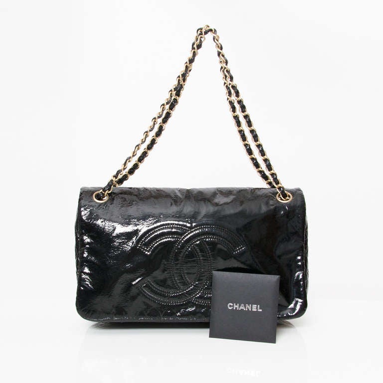 Chanel shoulder bag with large double 'C' logo stitched on the front flap. Made from black high-gloss patent vinyl. 
This slouchy style features crinkled black patent vinyl, a large stitched CC logo and handle details with gold-tone hardware