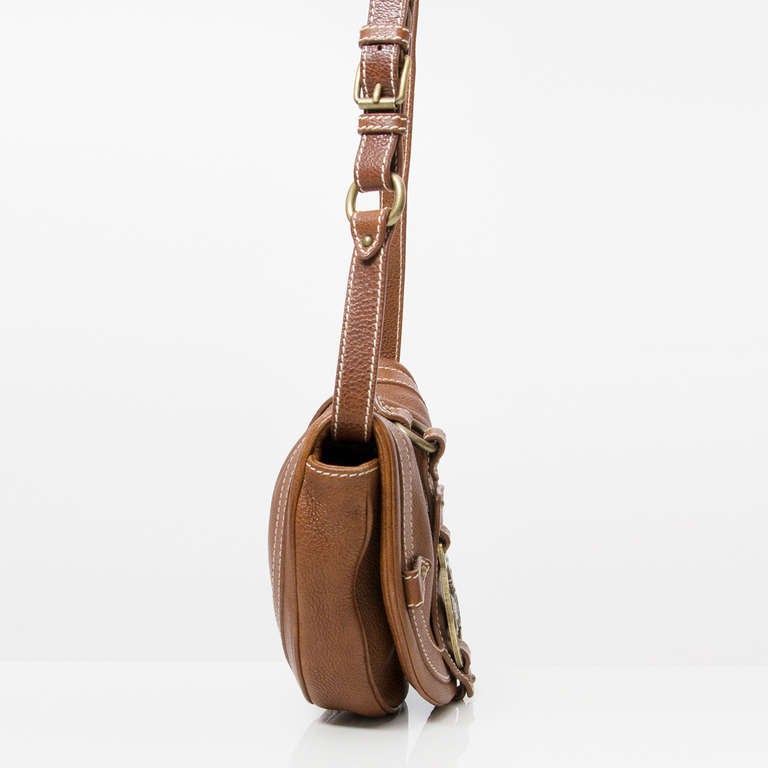 Céline brown leather saddle shoulder bag. 

Céline horse and carriage logo at the front. Brass hardware. Adjustable shoulder strap. Magnetic snap closure beneath the flap. 

The interior features an open pocket and a pocket to hold a cell