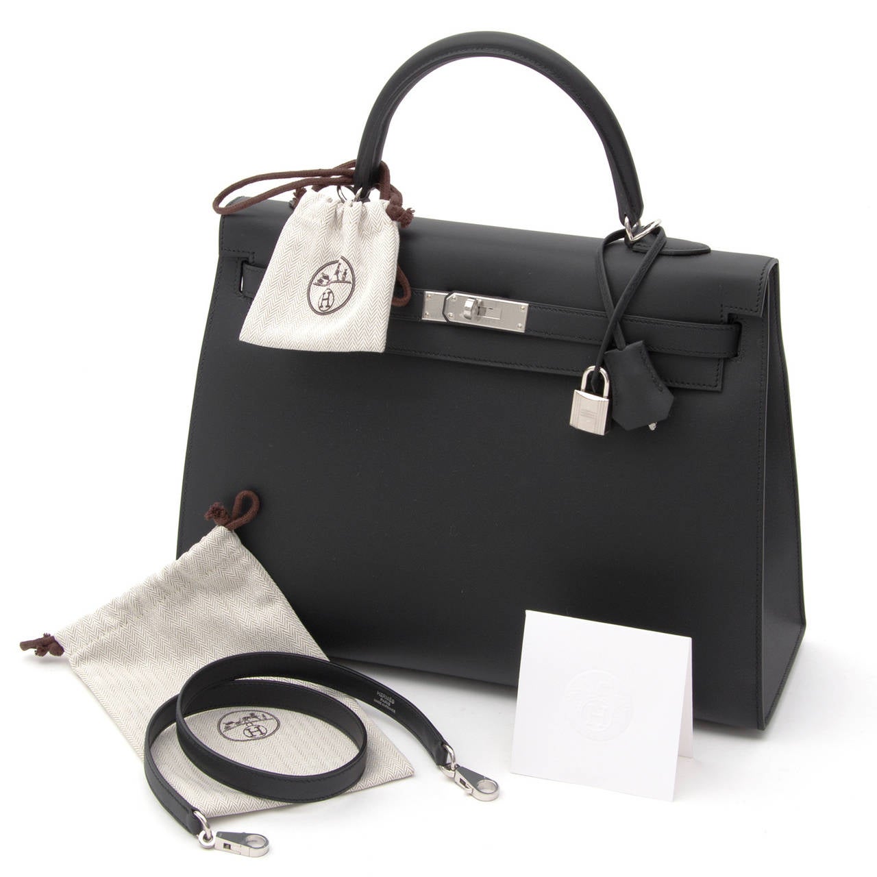 This brand new and Hermès Kelly bag in matte black Sombrero leather comes in its original invoice and box. It is packed with dustbag, raincoat, clochette cadenas keyholder and padlock. 

Nobody ever wore this bag. The plastic covers are still on