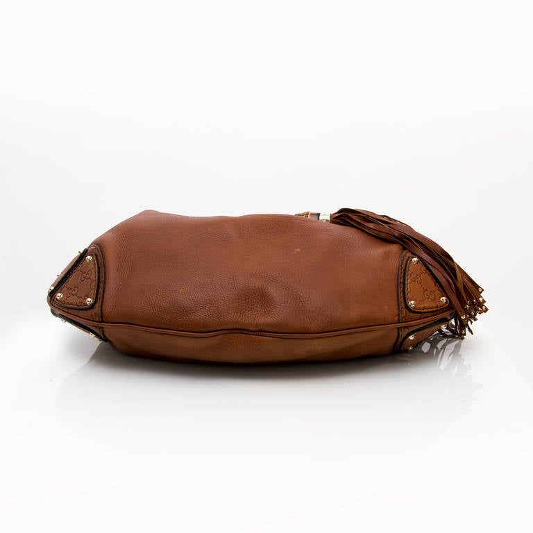 We can always count on Gucci for styles that we love now and later. This gorgeous Gucci Brown Leather Babouska Indy Top Handle Bag features a chic hobo design with a top handle with a metal Gucci logo, double tassels with bamboo details and 
