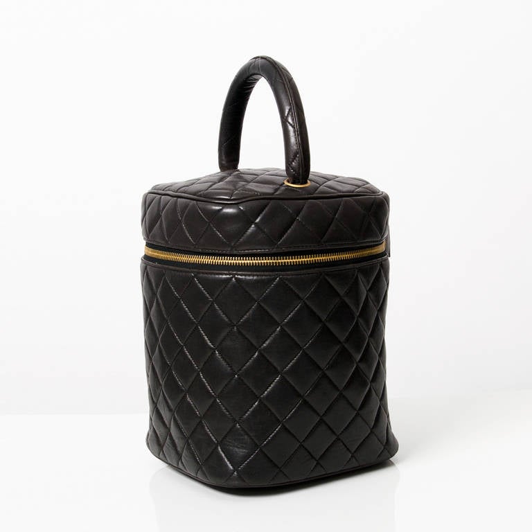 Chanel Vanity Cosmetic Black Quilted Bag. Handheld piece where the top is secured with zipper. Inside famous Chanel red leather lining with 3 elastic loops to keep its contents organized.