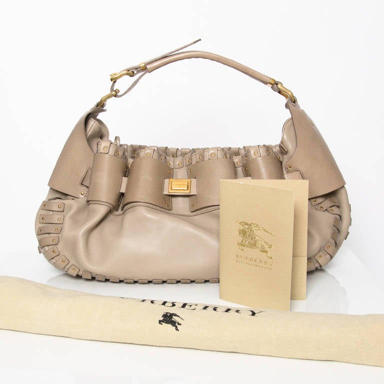 Burberry shoulder bag made from soft grained, but thick calfskin, very sturdy and durable feel! The color is a grey, beige or taupe hue. Yellow gold hardware throughout. 
Label inside: 'Made in Italy'  and on the reverse the fabrication code: