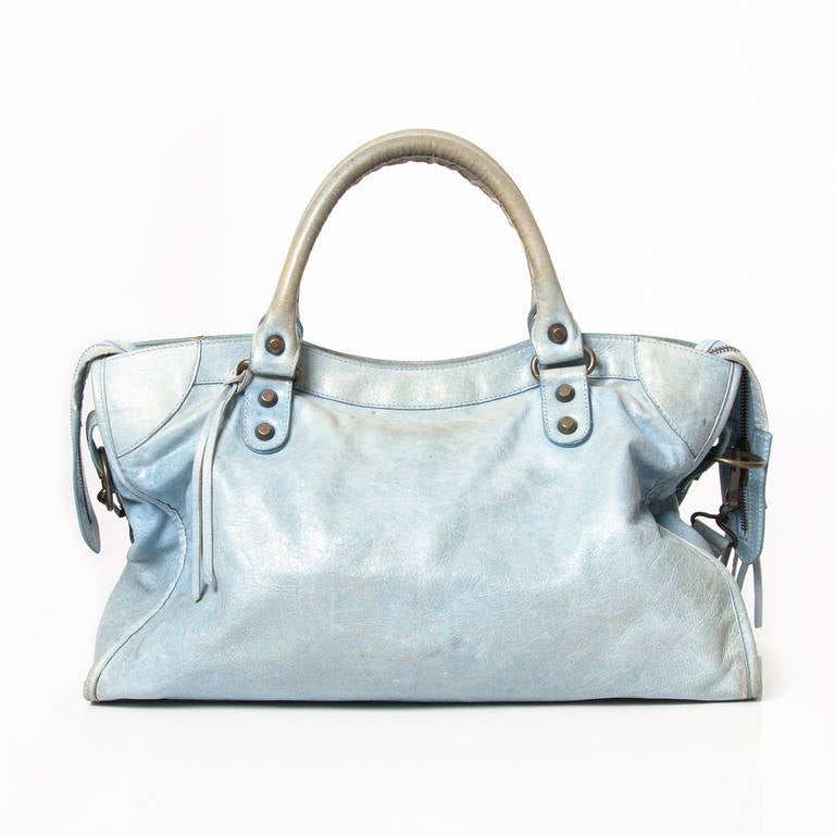 Baby blue classic city bag. Hand stitched handles Removable shoulder strap Top zip closure Aged brass hardware Leather tassel zipper pull and front zip pocket. Interior zip pocket with Balenciaga embossed leather label Leather framed mirror.