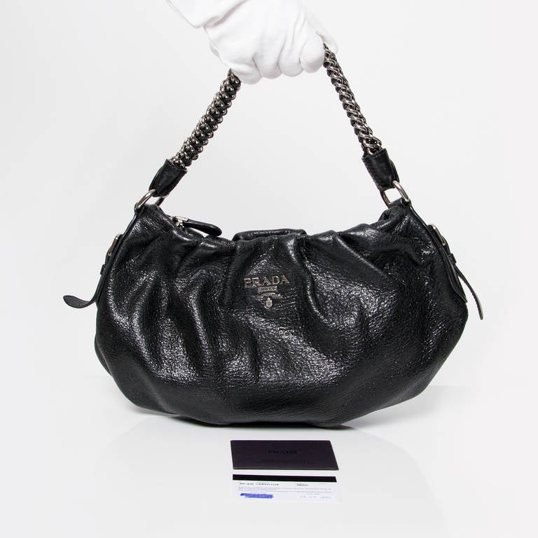Prada shoulder bag in pleated cervo lux leather with silver chain and hardware. One large zipper at the top. The interior features one zipped pocket. Comes with authenticity card.