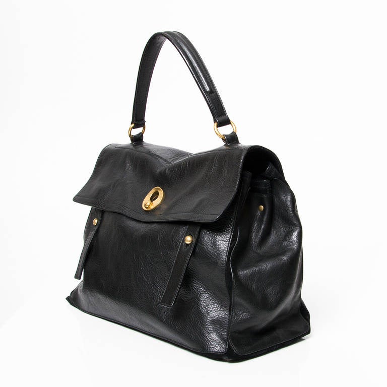 A hip top handle handbag with functional satchel straps, by Yves Saint Laurent In black leather. With aged gold-tone hardware.