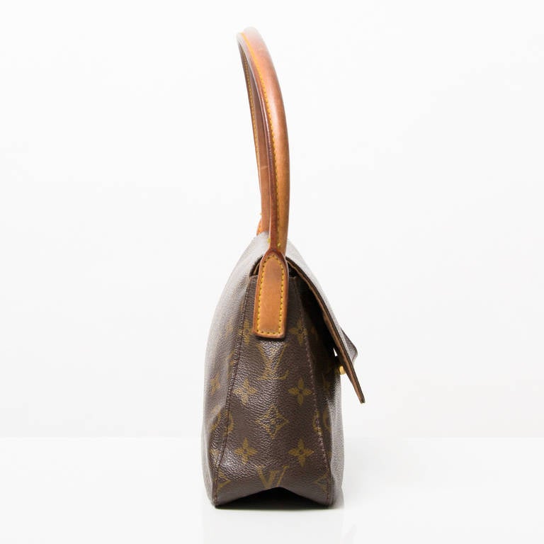 Louis Vuitton Monogram Mini Looping Shoulderbag  with goldtone hardware.
Foldover flap with snap closure.
Leather shoulder strap.
One inside zipper pocket.